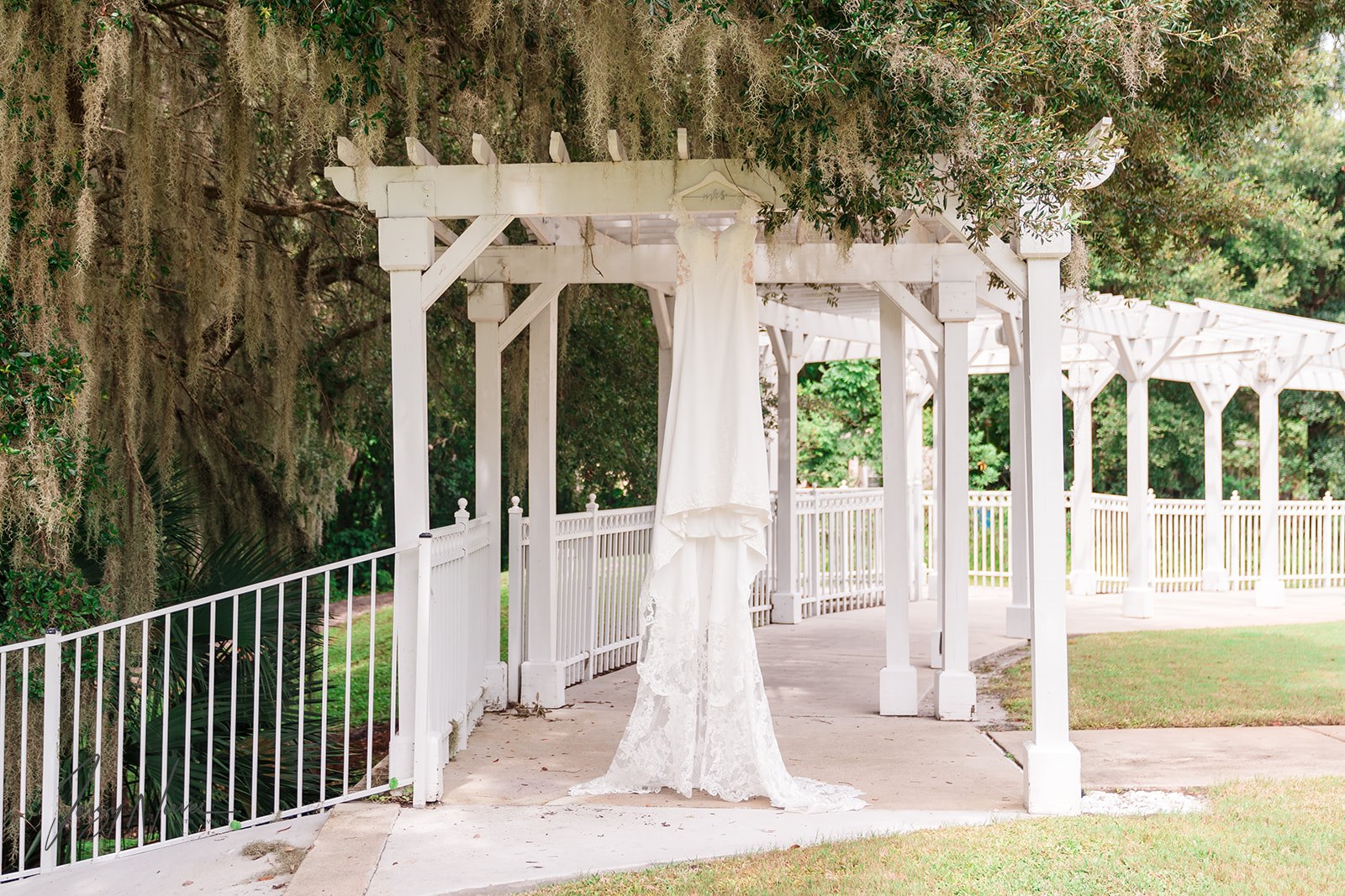 Shelby's wedding dress hanging elegantly from the archway in the outdoor walkway at Lake Mary Event Center