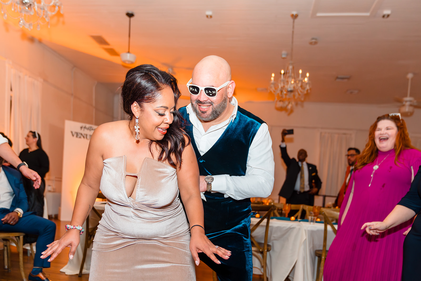 Fun moment of the couple dancing at Venue 1902, with the wife dancing on her husband wearing sunglasses, showcasing their unique personality.