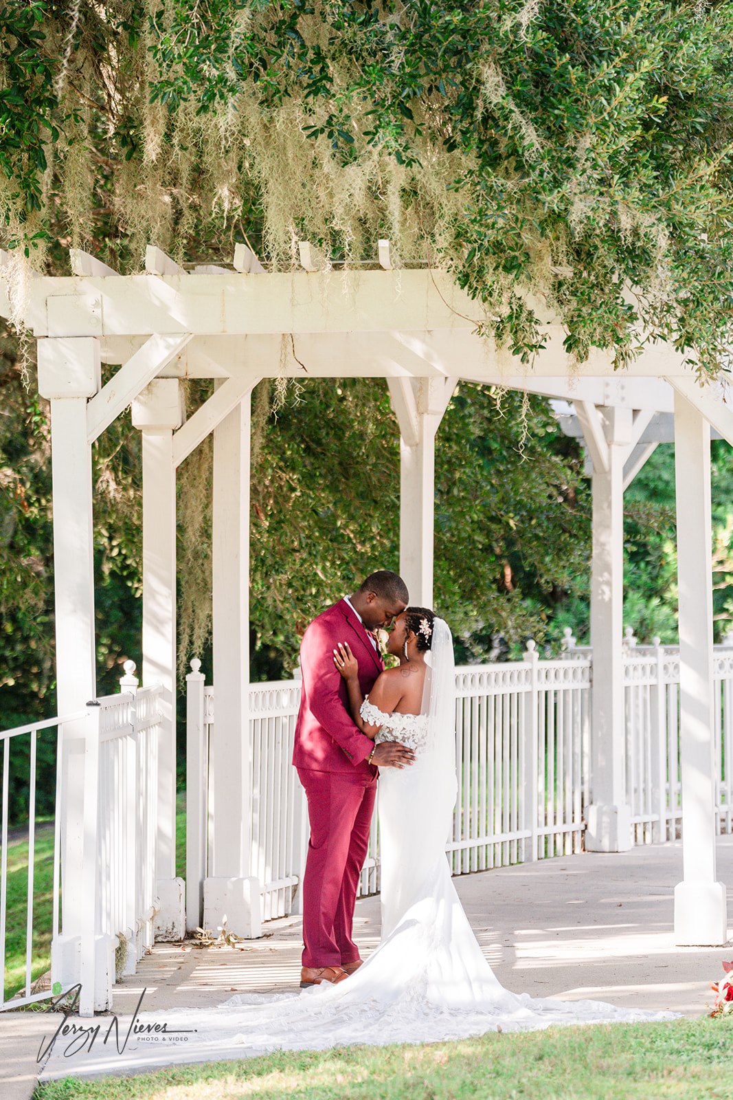Shelby and Javon sharing a tender embrace under the garden walkway at Lake Mary Event Center.