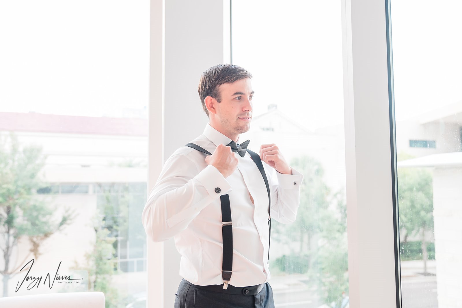 Groom looking out the window of the Dr. Phillips Performing Arts Center pre-wedding.