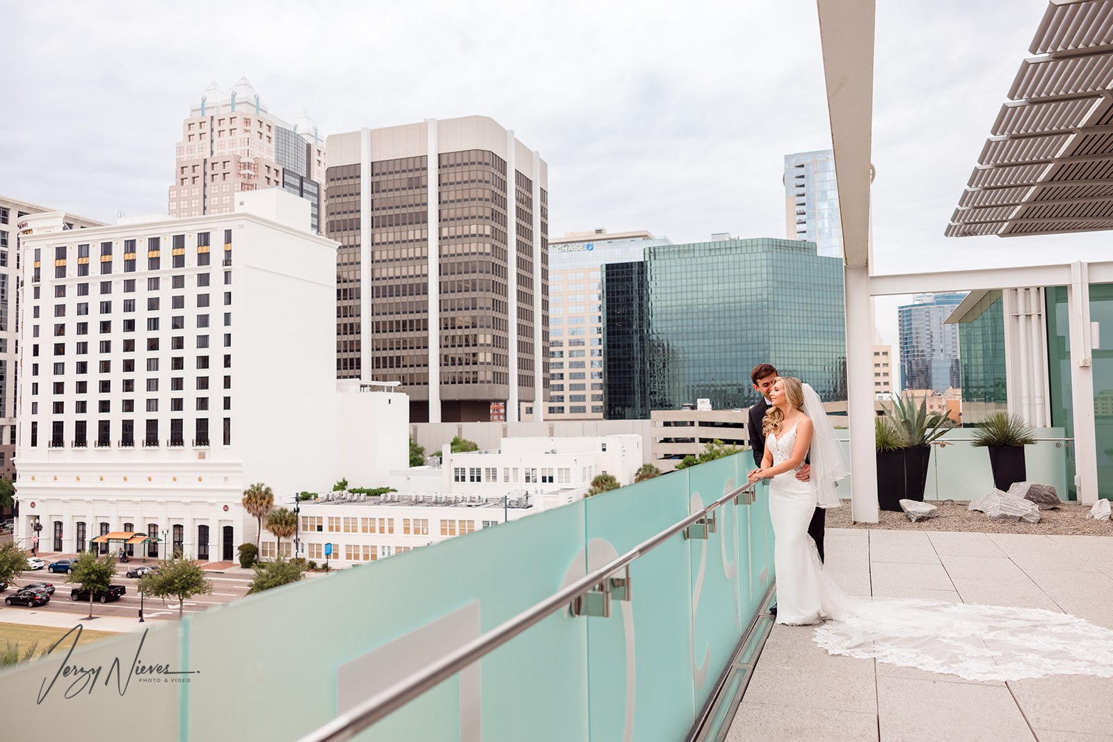 Newlyweds Brittany and Nathan embracing on the balcony of the Dr. Phillips Center for Performing Arts with Downtown Orlando in the background.