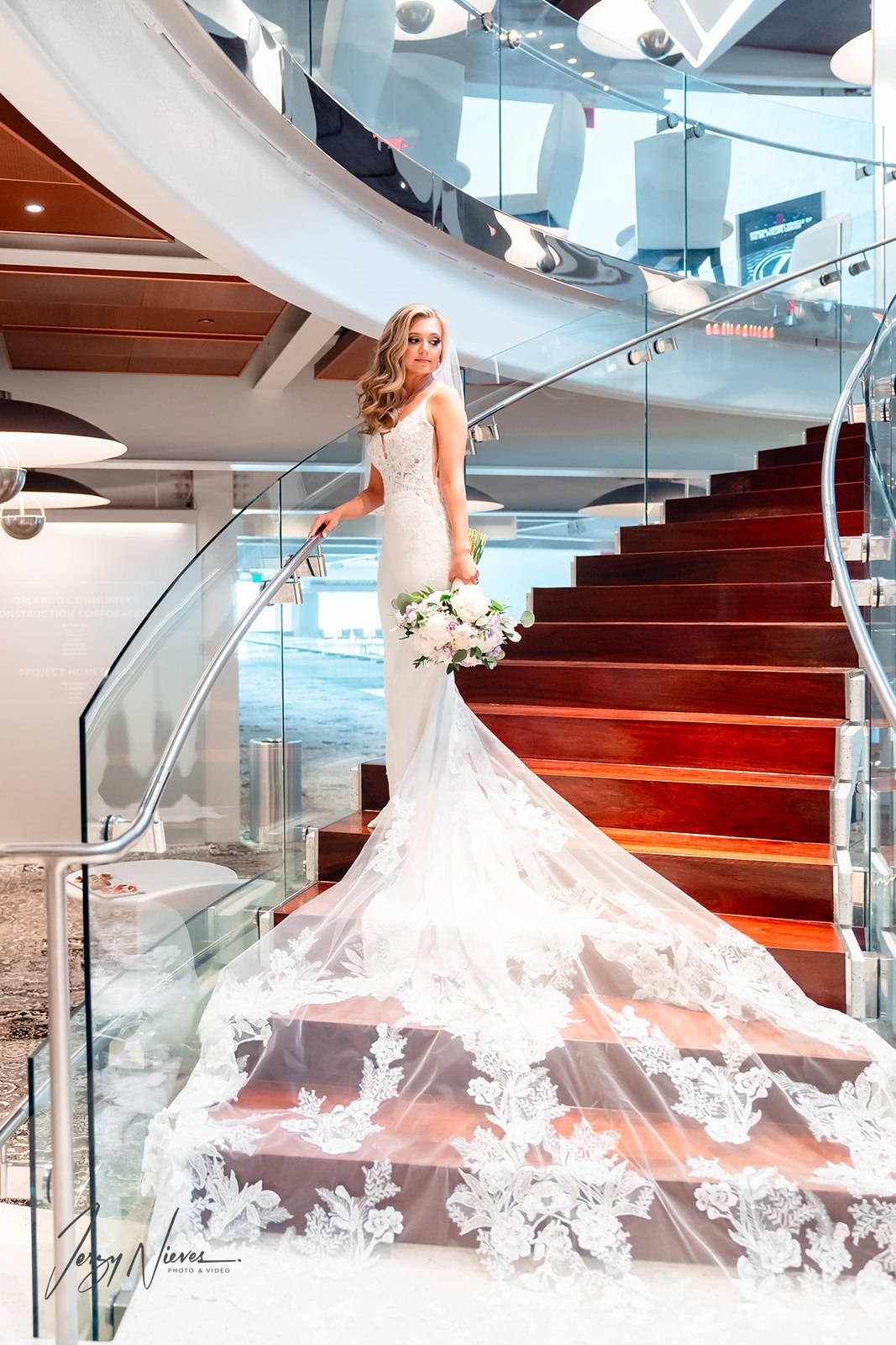 Bride descending the stairs of the Dr. Phillips Center in her wedding dress, the flowing fabric cascading gracefully behind her.