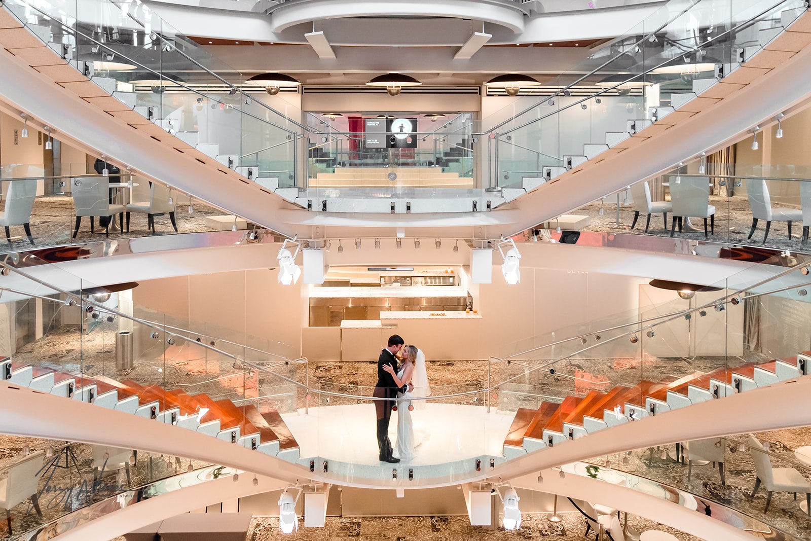 Bride and groom Brittany and Nathan embracing on the central staircase at Dr. Phillips Center for Performing Arts, showcasing the building's architecture and their love.