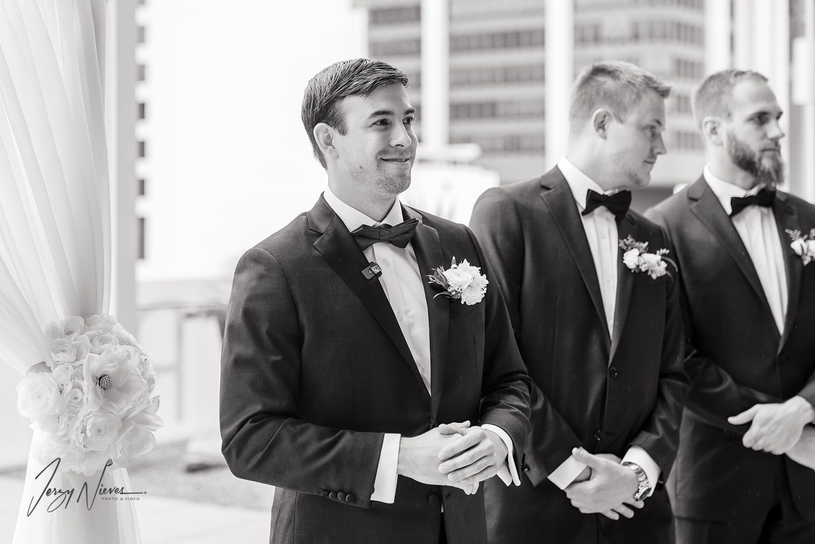 Black and white photo of groom Nathan watching his bride Brittany come down the aisle with his groomsmen by his side at Dr. Phillips Center for Performing Arts.