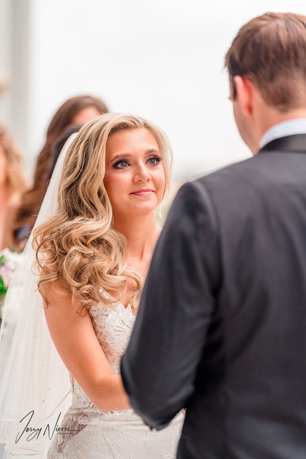 Over-the-shoulder shot of Nathan giving vows to Brittany at the altar, holding her hands as she looks at him intently.