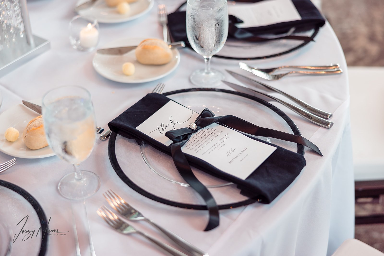 Close-up of a guest table set with elegant tableware and a thank you note placed on each plate.