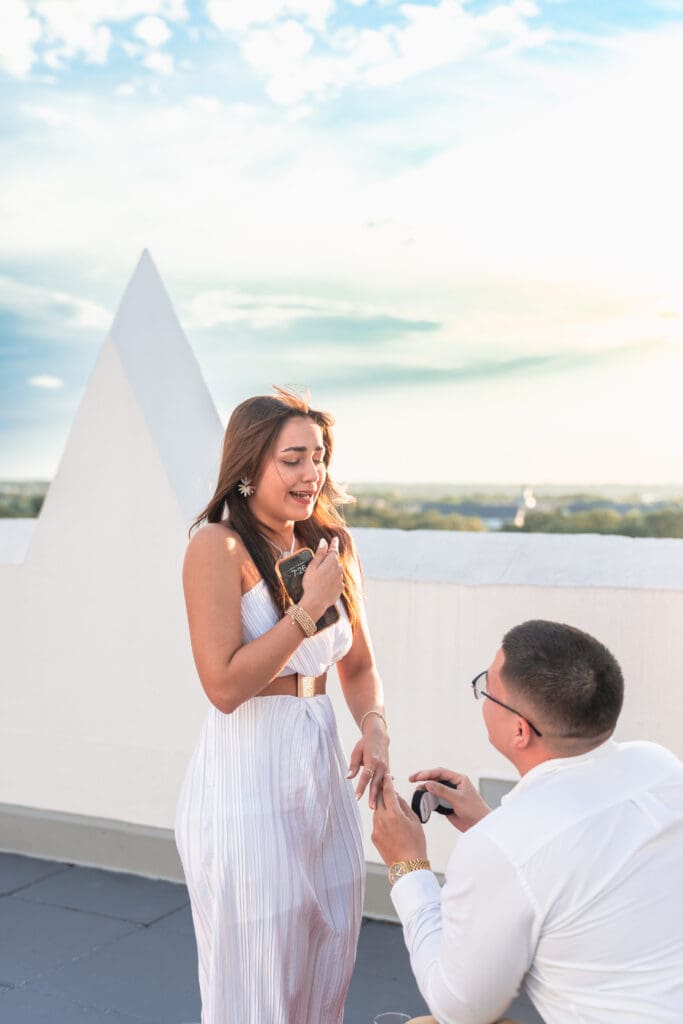 Bride-to-be on the verge of tears as the groom places the ring on her finger.