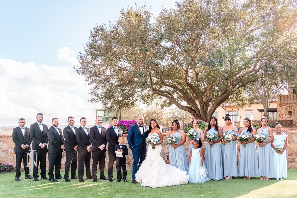 bridal party wearing blue under Italian Cypress Tree at Bella Collina