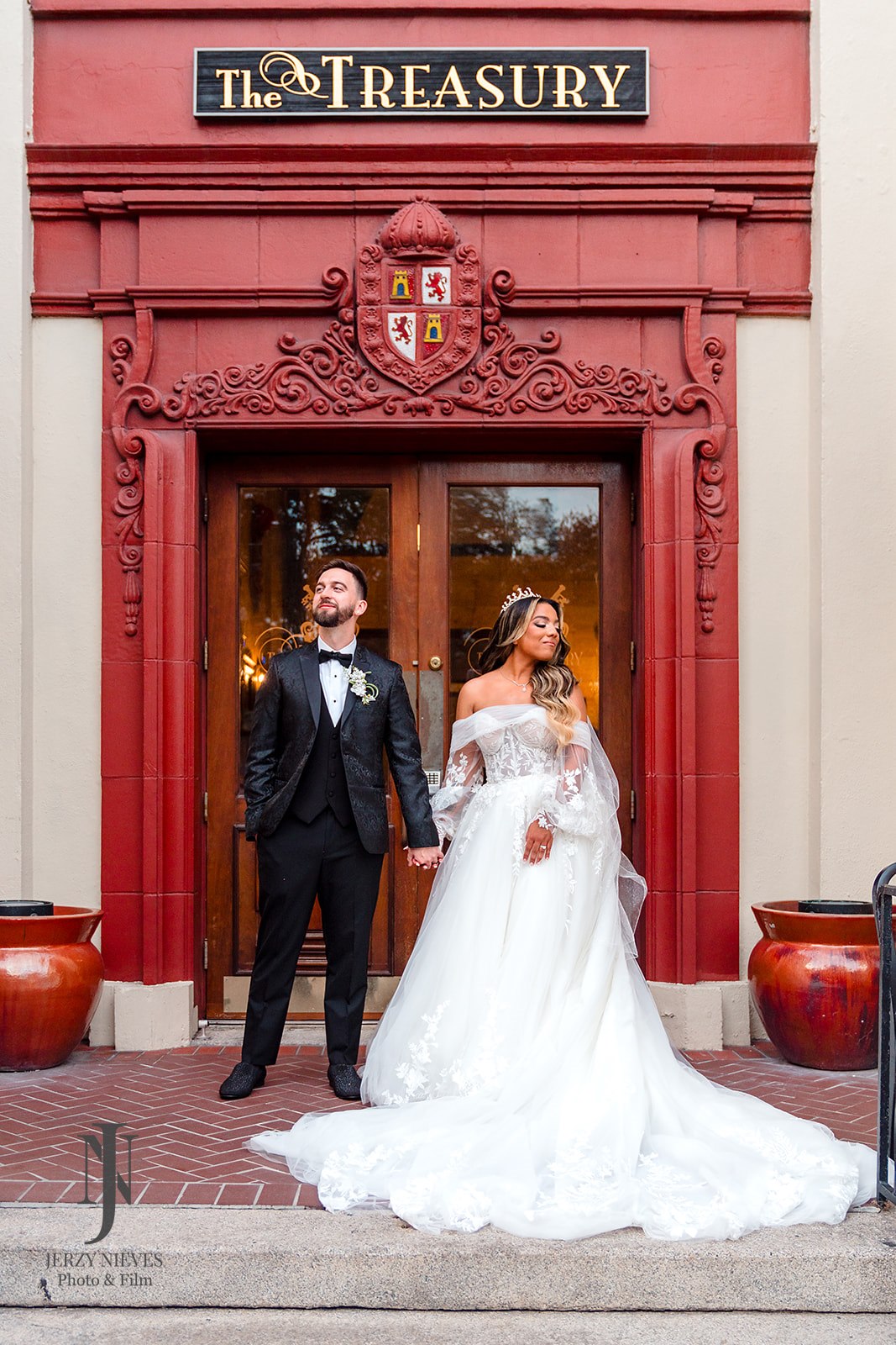 bride and groom portraits in front of red door at The Treasury on the Plaza