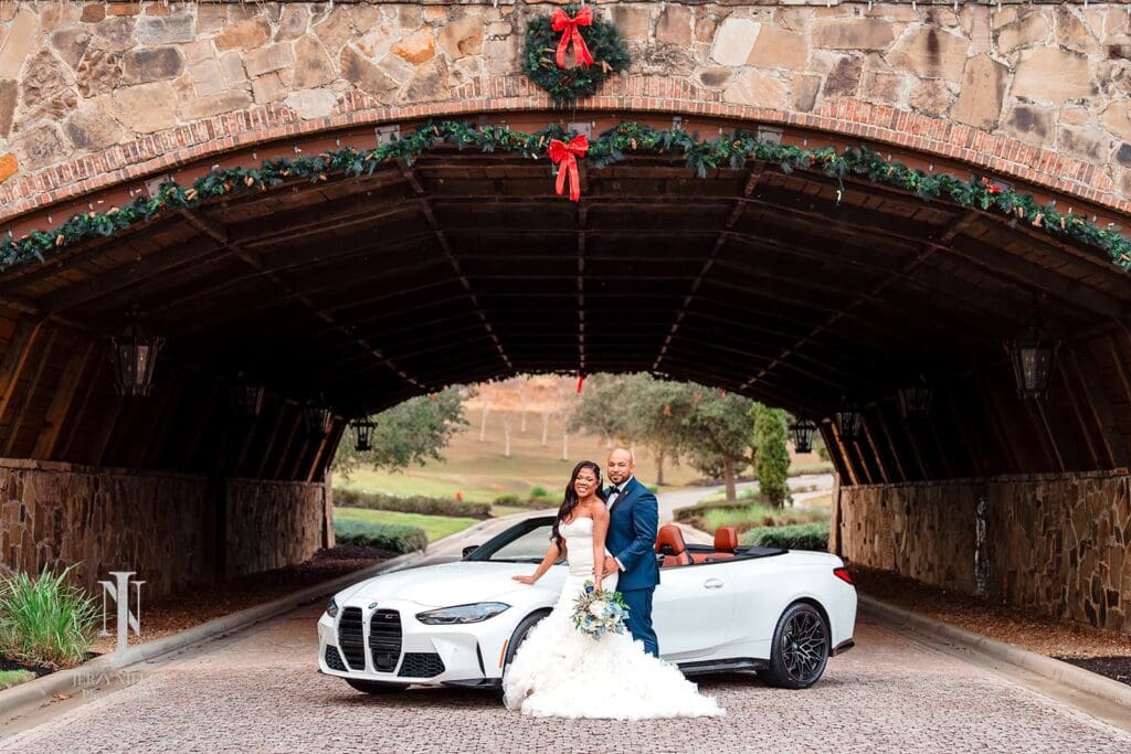 bride and groom standing by white BMW at Bella Collina Bridge