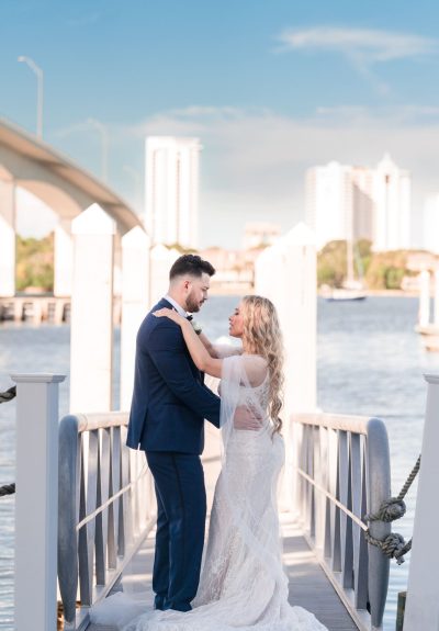 Jenn and Jazer embracing on the tall dock at Sunset Harbor, with ocean in the background.